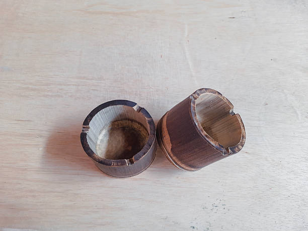 Two hollow wooden cylinders sit on a pale wood table, showing natural grain textures and rough edges. Ideal for stock photos of woodworking, crafts, or rustic home decor