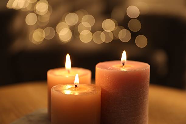 istock Burning candles on table against blurred lights indoors, closeup 2253939429
