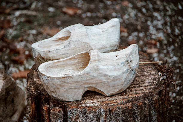 Pair of legs dressed with wooden shoes standing in grass.