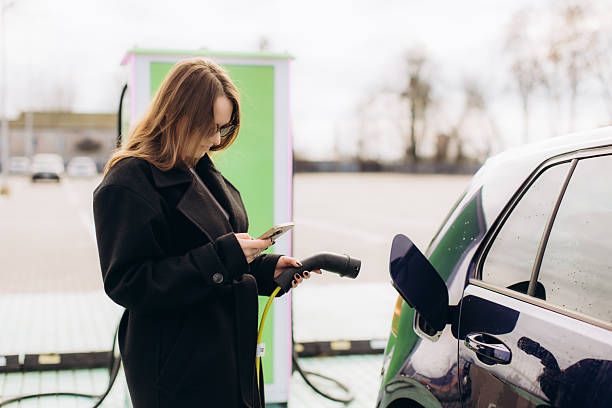 istock Woman using phone charging electric vehicle 2253942346