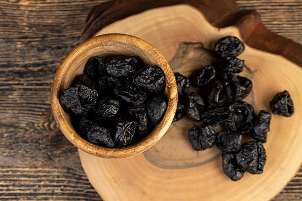 istock black soft dehydrated black plums, prunes scattered on the kitchen table, black sweet seedless prunes scattered on the table 2253950823