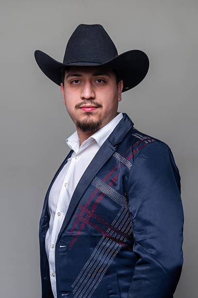 istock Hispanic man wearing a jacket and a cowboy hat looking at the camera on gray background 2253964872