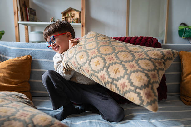Boy playing with a pillow on the sofa in a cozy home living room