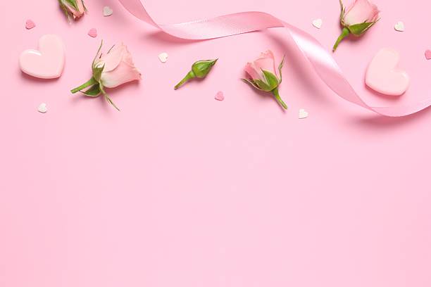 istock Beautiful composition with pink roses, hearts and silk ribbon on a colored background 2253967495