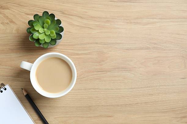 istock Office table with notebook, pen, coffee cup and green plant, top view 2253969202