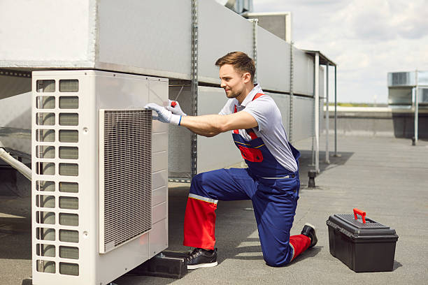 istock Technician installing and fixing air conditioner using screwdriver sitting on the roof of building. 2253969239