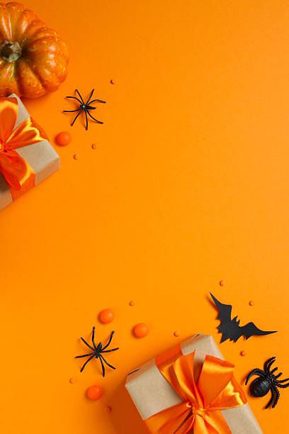 istock Top view of bright Halloween gift boxes and pumpkin decorations festively arranged on a orange surface. Happy Halloween holiday concept 2253969493