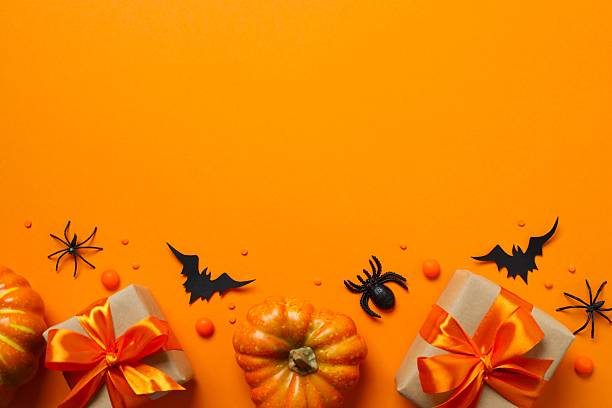 istock Top view of bright Halloween gift boxes and pumpkin decorations festively arranged on a orange surface. Happy Halloween holiday concept 2253969546