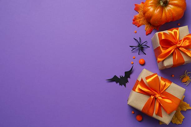 istock Halloween composition. Gift boxes, pumpkins, black bats and spiders on bright purple background, top view 2253969970