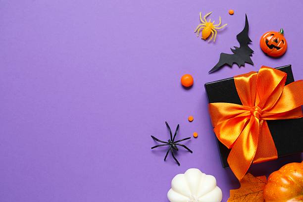 istock Halloween composition. Gift box, pumpkins, black bats and spiders on bright purple background, top view 2253970026