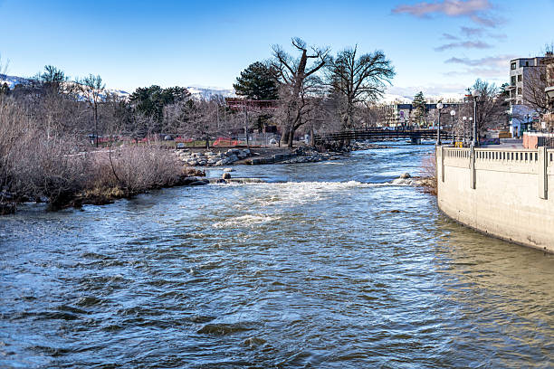 Truckee River in Wingfield park downtown Reno with snowcapped mountains and a clear blue sky in the background.