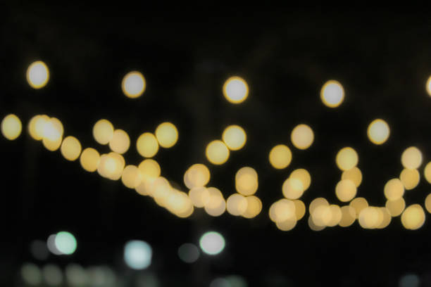 a beautiful bokeh effect created by blurred, warm-toned string lights against a dark background. dreamy wedding or event atmosphere or holiday banner.