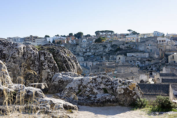 panoramic view of matera sassi, ancient stone cave dwellings carved into cliffs under a clear blue sky, iconic italian historical landmark in basilicata