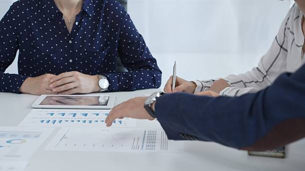 istock Business people examining and discussing financial documents, studying performance charts on paper and digital tablet during collaborative meeting in modern office 2253982725