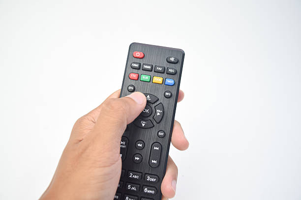 istock Human hand holding and pressing a black TV remote control isolated on white background 2253987783