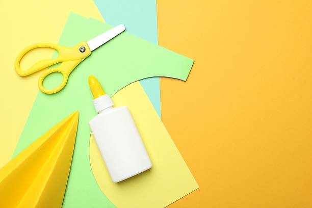 istock Glue, scissors, handmade plane and color paper on yellow background, flat lay. Space for text 2253992310