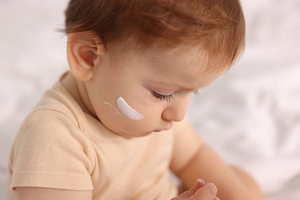Cute baby with cream on his face at home, closeup