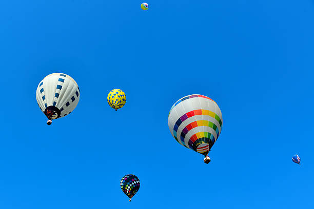 istock Colorful hot air balloons with a basket below float against a clear blue sky. 2253995737