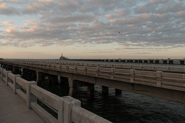 A wide sunset view along a pier with the  Skyway Bridge on the horizon and soft evening clouds overhead. Great for Florida coast, travel planning, and calm end-of-day visuals