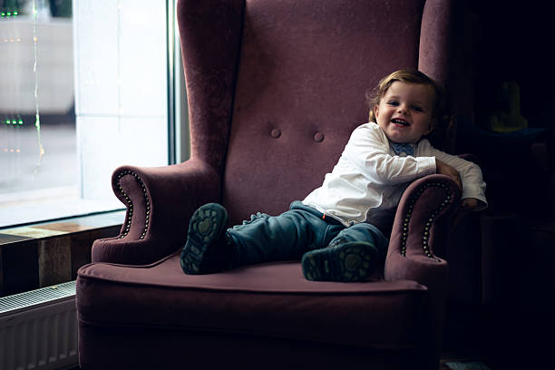 Happy little girl day sitting on chair at balcony and looking at camera.