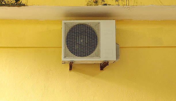 istock Outdoor Air Conditioner Compressor Unit Mounted on Yellow Wall System for Residential or Commercial Cooling Ventilation and HVAC Maintenance Services 2254007232