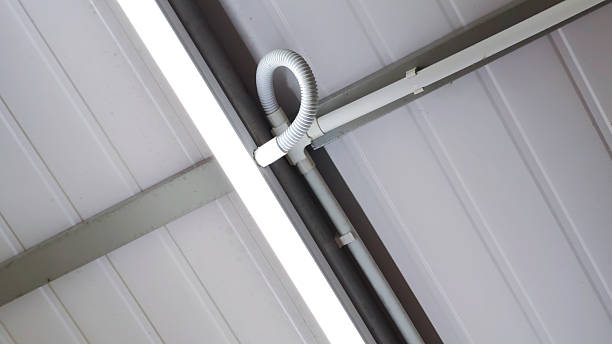 istock Modern Electrical Conduit and Flexible Piping Installed on White Corrugated Ceiling with Bright LED Tube Light for Industrial Warehouse or Office Maintenance Concept 2254007235