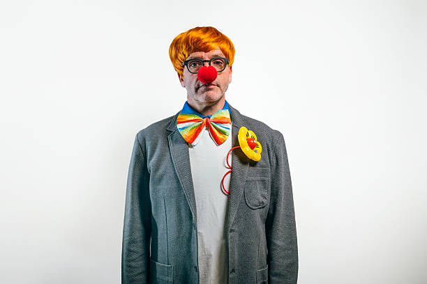 Man dressed as business clown with serious expression and colorful accessories