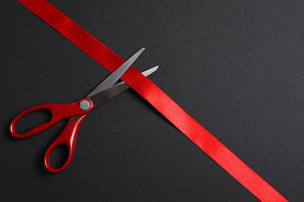 istock Beautiful red ribbon and scissors on black background, flat lay with space for text. Ceremonial tape cutting 2254017582