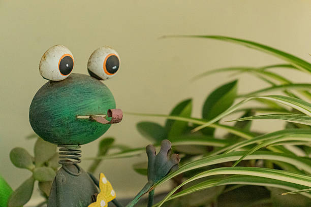 A whimsical frog ornament looks toward fresh green leaves symbolizing curiosity nature and playfulness. Ideal for lifestyle campaigns eco concepts or creative editorial projects.