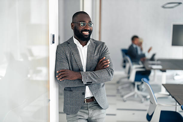 istock Confident Black Professional In Glass Office Smiles While Leaning Against Wall In Modern Conference Room 2254019638