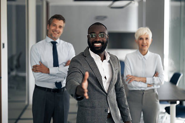 istock Confident Professional Extends Hand In Modern Office With Two Smiling Colleagues 2254019712