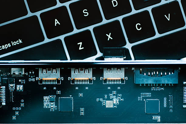 Close-up view of a laptop keyboard next to an exposed electronic circuit board, representing technology, hardware, computer engineering, and digital devices.