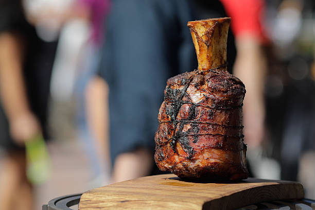 Roasted beef knuckle on a wooden table outside on a sunny day.