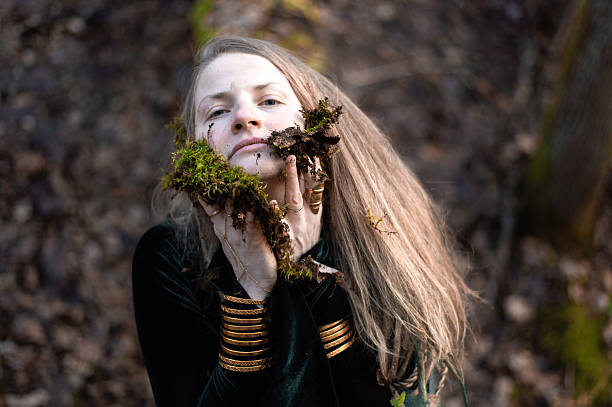 Beautiful teenage girl in princess outfit on a walk. She is hiding in the foliage lost in the forest. Shooting on a summer night in a forest area