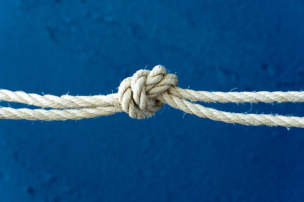 A close-up view of a securely tied rope and knot on a ship mast, highlighting the essential rigging used in maritime navigation.