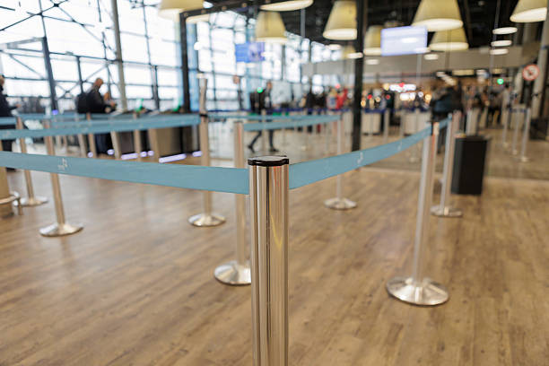 istock Blue queue barriers in empty airport security area with people in background 2254034226