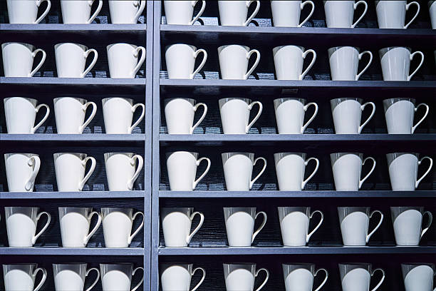 Some white ceramic mugs arranged in storage racks.
