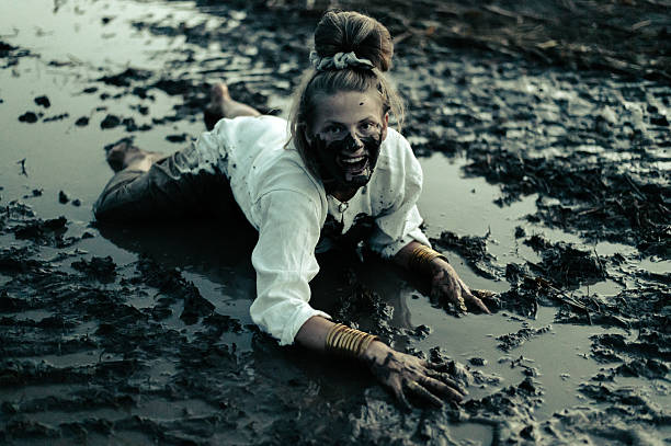 A happy authentic woman stuck in a mud puddle in a field