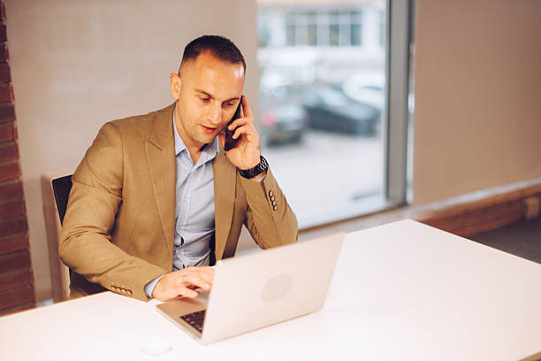 istock Businessman talking on phone working on laptop in office 2254040639