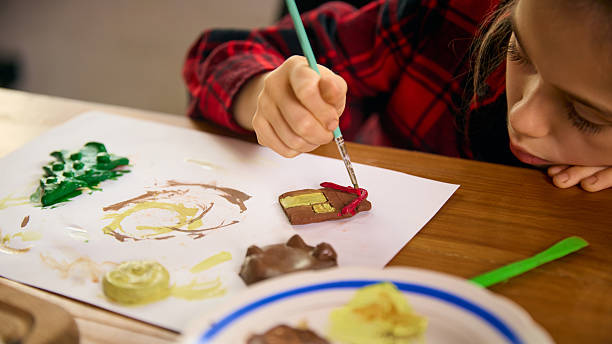 istock Girl decorating clay house and tree figures with bright colors 2254049447