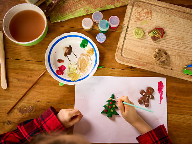 istock Child decorating clay Christmas tree and gingerbread figurines on paper 2254049455