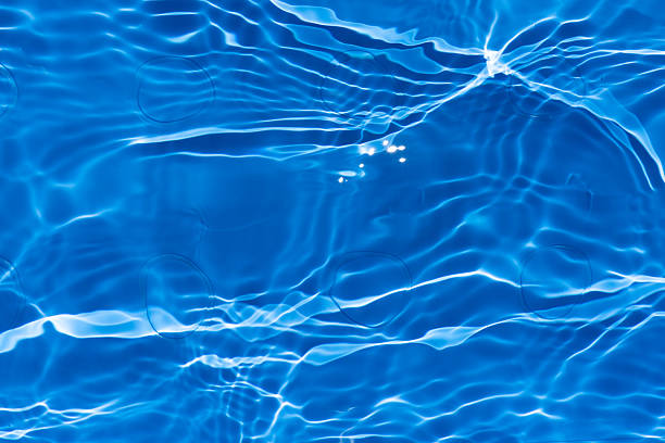 A vibrant summer photo showcasing the crystal-clear blue water of a swimming pool under the bright sun, evoking feelings of refreshment and relaxation.