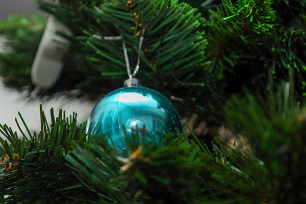 istock A glossy blue ball hangs gracefully on a silver thread among thick green branches of a Christmas tree. This classic holiday tree with a bright ornament creates a festive mood and a cozy winter atmosphere, perfect for seasonal home decoration. 2254050882