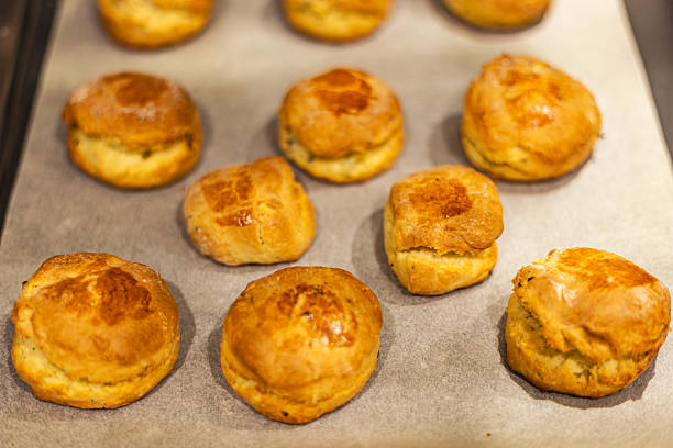 Scones, with their enticing golden color and natural cracks, appear on baking paper, creating a warm and fragrant baking atmosphere.