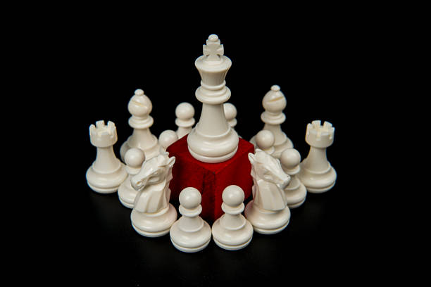 Central white king elevated on red pedestal surrounded by chess pieces representing authority, strategic control, leadership command, and organizational hierarchy in business environments.