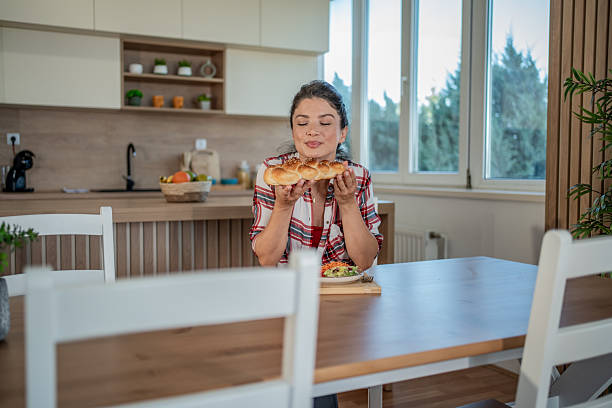 Woman smelling fresh baked braided bread in kitchen