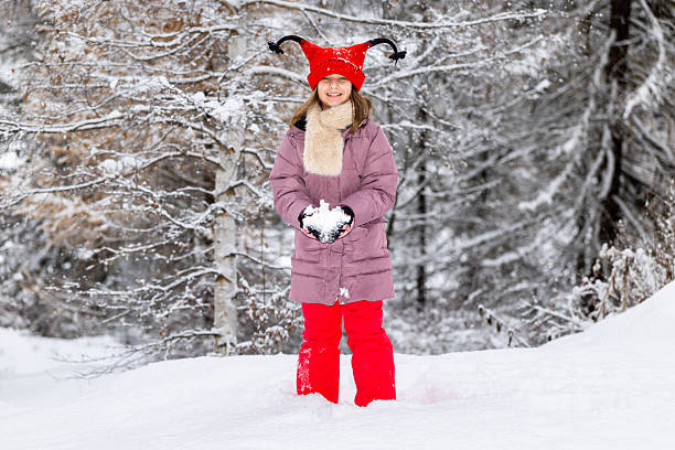 A cute little girl dressed in red stands out against the white winter landscape of the meadows and woods around Cogne, in the Aosta Valley. She is very happy about the snowfall on Christmas Day.