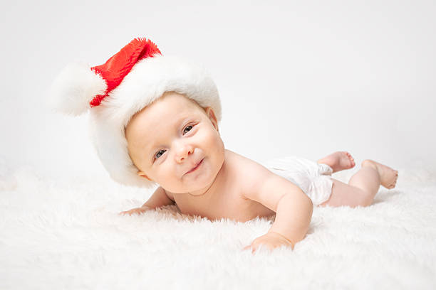 An adorable 6 month old Caucasian baby boy wearing a Santa hat celebrating his first Christmas.