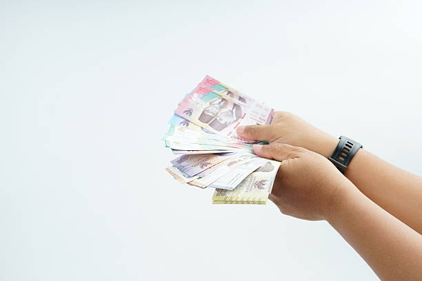 istock Hand holding Indonesian rupiah banknote on white background representing cash payment, personal finance, income, and financial transaction with clean minimal composition. 2254067621