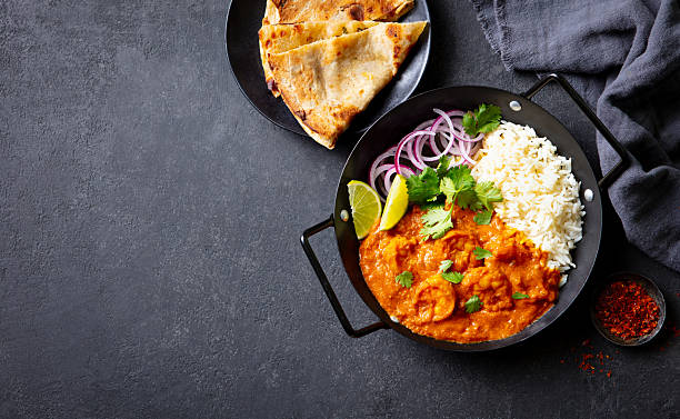 istock Shrimp curry with fragrant rice, crispy naan, fresh cilantro, lime wedges and aromatic spices. Grey background. Copy space. Top view. 2254067644